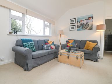 A living room with two gray sofas a wooden chest coffee table two floor lamps and artwork on the wall at Mackerel Sky in Marazion