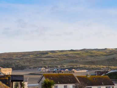 Sand dunes with buildings and roofs in the foreground at Alma House 2 in Perranporth
