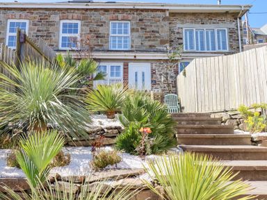 Stone house with white windows and door with stairs and various plants in the garden at Alma House 2 in Perranporth