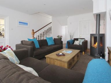 A living room with brown sofas blue cushions and a wooden coffee table near a fireplace at Porthcurno Bay View in Porthcurno