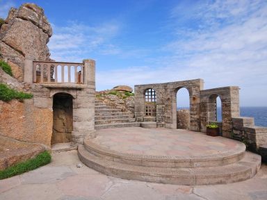 A stone outdoor amphitheater with steps and arched openings overlooking the sea at Porthcurno Bay View in Porthcurno