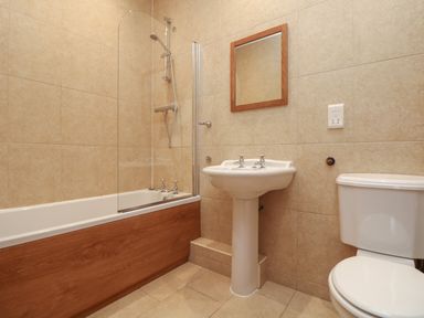 A bathroom with a bathtub shower combination a pedestal sink a toilet and a mirror at Willow in Falmouth
