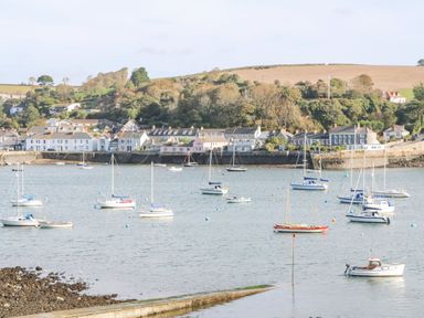 A harbor with sailboats anchored near a shoreline with houses and trees at Willow in Falmouth