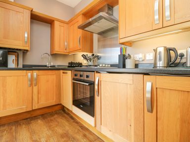 A kitchen with wooden cabinets a built in oven a sink and countertop appliances at Willow in Falmouth