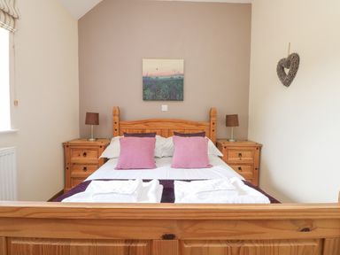 A bedroom with a wooden bed and bedside tables with lamps at Willow in Falmouth