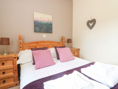 A bedroom with a wooden bed frame and two bedside tables with lamps at Willow in Falmouth