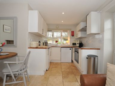 A kitchen with a window, appliances and a table at Stocks Barn Looe