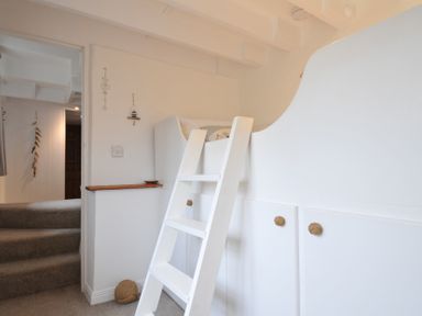 A staircase with a ladder and shelf at Stocks Barn in Looe