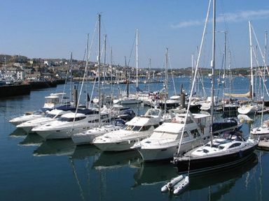 Yachts and sailboats docked at a marina with buildings in the background at Halvosso in Falmouth