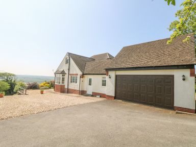 An exterior view of a house with a double garage door and gravel driveway at Charlesworth in Braunton