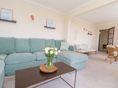 A living room with a blue sectional sofa and a coffee table with flowers at Charlesworth in Braunton
