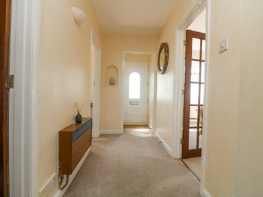 A hallway with a carpet and a white front door at Charlesworth in Braunton