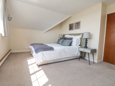 A bedroom with a bed bedside tables lamps and two pictures on the wall at Charlesworth in Braunton