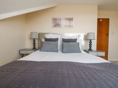 A bedroom with a bed with pillows and lamps on bedside tables at Charlesworth in Braunton