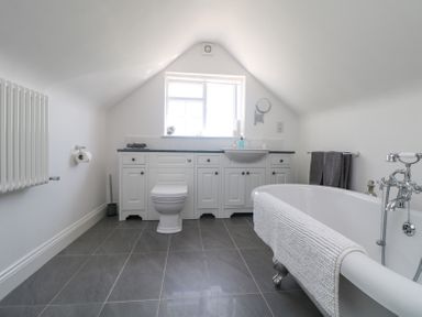 A bathroom with a toilet sink and bathtub under a sloped ceiling at Charlesworth in Braunton