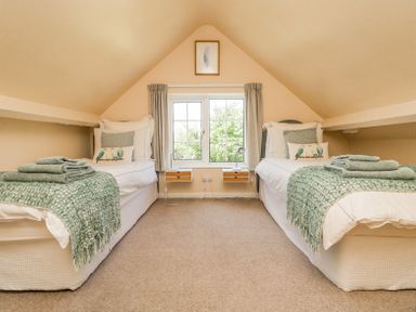 A bedroom with two single beds and green blankets under a window at Charlesworth in Braunton