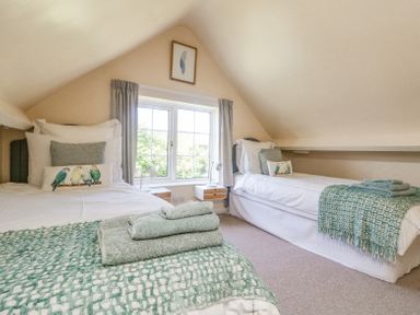 A bedroom with two single beds with towels and cushions near a window at Charlesworth in Braunton
