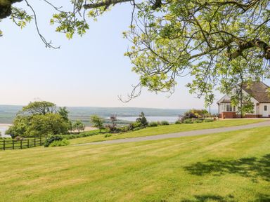 A house with lawn and trees overlooking a river at Charlesworth in Braunton