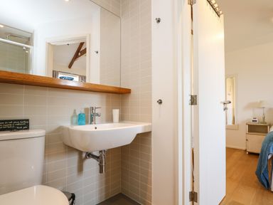 A bathroom with a toilet and sink next to a doorway leading to a bedroom at Sundowner in Padstow