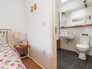 A bedroom with a bed and bedside table next to a bathroom with a sink and toilet at Sundowner in Padstow