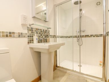 A bathroom with a pedestal sink toilet and glass shower enclosure at The Old Barn in Sennen
