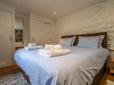 A bedroom with a double bed with folded towels on the bed and sliding closet doors at Barneys Barn in Sennen