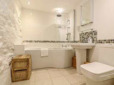 A bathroom with a bathtub shower combination a sink and a toilet at Barneys Barn in Sennen