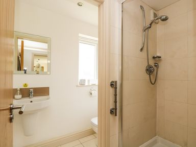 A bathroom with a shower area to the right and a sink with a mirror on the left at Ridgeback House in Mullion