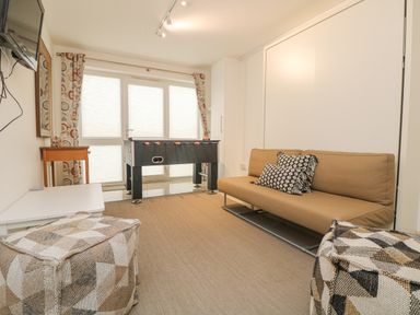 A game room with a foosball table brown sofa cushions and patterned ottomans at Ridgeback House in Mullion