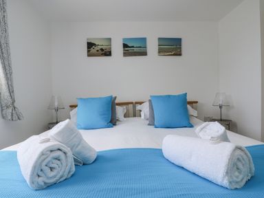 A bedroom with a bed and towels arranged at Ridgeback House in Mullion
