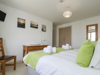 A bedroom with a bed and chair at Ridgeback House in Mullion