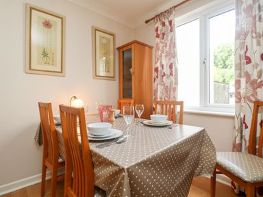A dining room with a wooden table covered with a polka dot tablecloth and wooden chairs at Tre Pol Pen in Falmouth