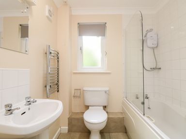 A bathroom with a sink a toilet a window a heated towel rail and a bathtub with a shower at Tre Pol Pen in Falmouth