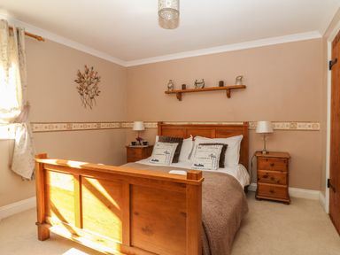 A bedroom with a wooden bed frame bedside tables and a shelf at Speedwell in Charlestown