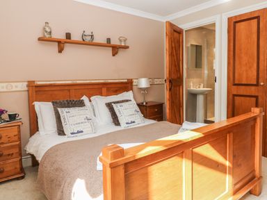 A bedroom with a wooden bed frame pillows bedside tables and an open door to a bathroom at Speedwell in Charlestown