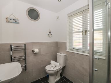 A bathroom with a toilet rolled towels a sink a window with blinds and a towel rack at Speedwell in Charlestown
