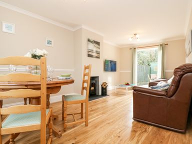 A dining and living room with wooden chairs and a table beside brown leather sofas at Speedwell Charlestown