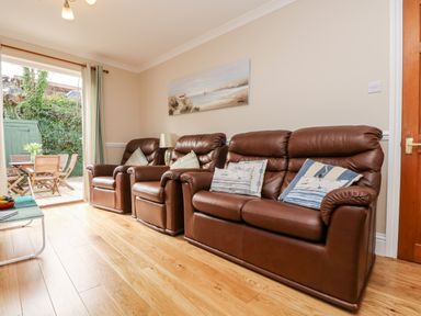 A living room with brown leather sofas and cushions next to a door opening to an outdoor patio at Speedwell in Charlestown