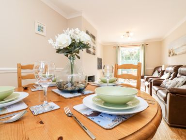 A dining table with plates glasses and a flower vase in a living room with sofas at Speedwell in Charlestown