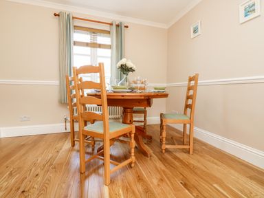 A dining room with a wooden table and four chairs with green cushions at Speedwell in Charlestown