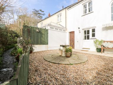 A gravel courtyard with potted plants a small water feature wooden bench and a stream beside the fence at Speedwell in Charlestown