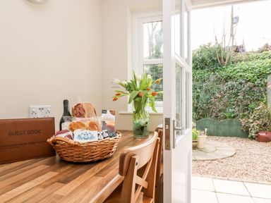 A wooden table with a basket of food items and a vase of flowers next to an open door leading to a garden at Speedwell in Charlestown