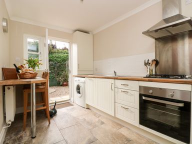 A kitchen with a wooden counter table and chairs a washing machine an oven and a door leading outside at Speedwell in Charlestown