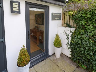 A glass door entrance with two potted plants and a sign reading Anneth Lowen 15 Riverside at Anneth Lowen in Angarrack near Hayle