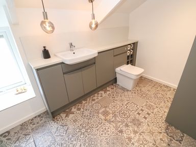 A bathroom with patterned floor tiles a sink grey cabinets and a toilet at Anneth Lowen in Angarrack near Hayle