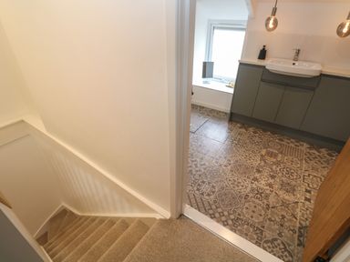 A stairway with carpeted steps leading to a bathroom with patterned tiled floor and a vanity unit at Anneth Lowen in Angarrack near Hayle