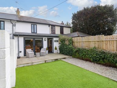 A backyard with artificial grass patio furniture and a wooden fence at Anneth Lowen in Angarrack near Hayle