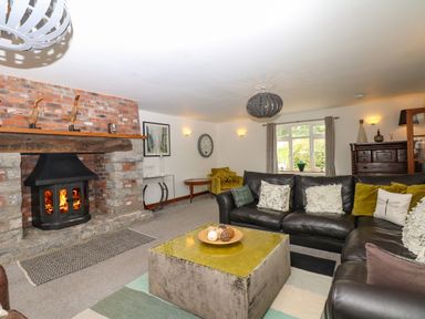 A living room with a fireplace black leather sofas and a large square coffee table at Nairn in Braunton