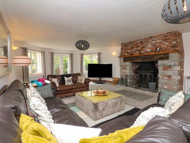 A living room with leather sofas a coffee table a large fireplace and a television at Nairn in Braunton