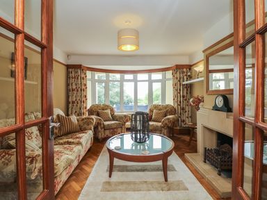 A living room with floral sofas and armchairs a glass coffee table and a fireplace at Nairn Braunton